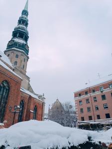 una iglesia con una torre de reloj en la nieve en Old Town Retreat with Stunning Views 2 bedroom Apartment en Riga