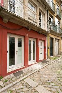 um edifício vermelho com portas brancas e uma varanda em Aposentus - St Francisco Studio 20 no Porto