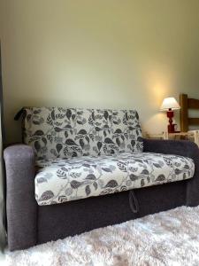 un sofá sentado en una sala de estar junto a una lámpara en Namata CHALÉS en Nova Friburgo