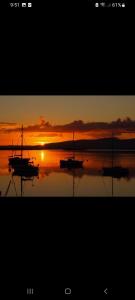 two boats sitting in the water at sunset at Panoramic Harbour View Apartment in Oban