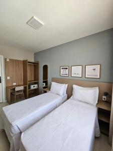 2 camas en una habitación de hotel con sábanas blancas en Aero Hotel, en Lauro de Freitas