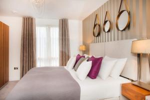 een slaapkamer met een groot bed met paarse en witte kussens bij Stylish and central two bedroom & two bathroom apartment with free parking in Bath