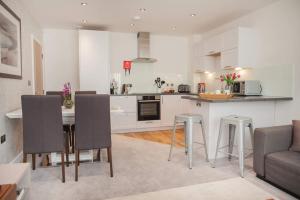 a kitchen and living room with a table and chairs at Stylish and central two bedroom & two bathroom apartment with free parking in Bath