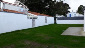 einen Hinterhof mit einem weißen Zaun und grünem Gras in der Unterkunft Un petit coin de paradis in Barbâtre