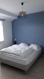 Bett in einem Zimmer mit blauer Wand in der Unterkunft Un petit coin de paradis in Barbâtre