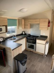 a kitchen with a stove and a sink at Luxury Hot Tub Caravan Tattershall in Tattershall