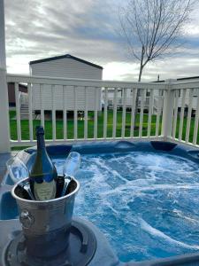 a bucket with a bottle of wine and glasses next to a hot tub at Luxury Hot Tub Caravan Tattershall in Tattershall