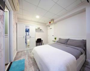 a bedroom with a large white bed and a desk at Pillows CoLiving in Hong Kong