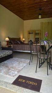 uma sala de estar com uma cama, uma mesa e cadeiras em Namata CHALÉS em Nova Friburgo