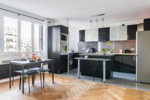 a kitchen with black cabinets and a table and chairs at Bel appartement 6 Pers bord Canal de l'Ourcq La Villette-PARKING in Paris