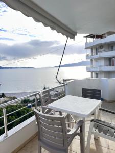 una mesa y sillas en un balcón con vistas al agua en Violet Sea View Apartment, en Sarandë