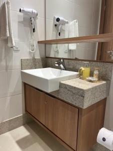 La salle de bains est pourvue d'un lavabo blanc et d'un miroir. dans l'établissement Conecta Flats - De frente para Pedra Azul, à Pedra Azul