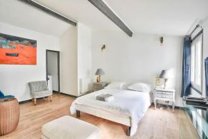 a white bedroom with a bed and a chair at Splendide T2 à proximité du Parc Georges Brassens in Paris