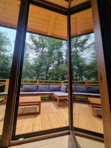 Habitación con sofá en una terraza de madera. en Chatka Przy Miedzy en Jabłonka