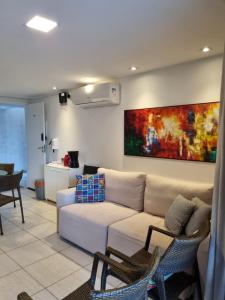 a living room with a couch and a painting on the wall at Porto Central Residence 01 in Porto De Galinhas