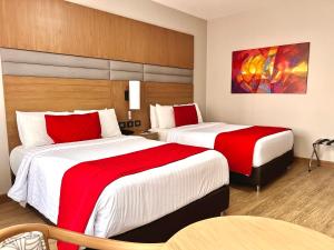 two beds in a hotel room with red and white sheets at Hotel Dann Carlton Cali in Cali