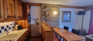 cocina con mesa de madera y pared de piedra en travelski home premium - Résidence Les Hauts Bois 4 stars, en Aime La Plagne