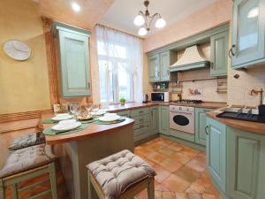 a kitchen with green cabinets and a table with chairs at Old Town Retreat with Stunning Views 2 bedroom Apartment in Riga