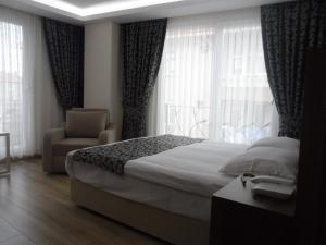 a bedroom with a bed and a chair and windows at Zen Inn Boutique in Şarköy