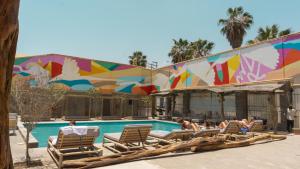 a group of people laying in lounge chairs by a swimming pool at Viajero Kokopelli Huacachina Hostel in Ica