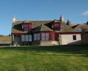 a large house with red windows on a green lawn at Craiglea Lodge in Latheron