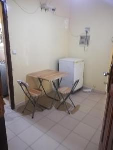 cocina con mesa, 2 sillas y nevera en Buzsahm en Dakar