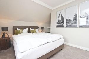 a bedroom with a large white bed with paintings on the wall at Apartment Ostseerausch in Scharbeutz