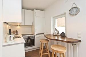a kitchen with white cabinets and a counter with stools at Apartment Ostseerausch in Scharbeutz