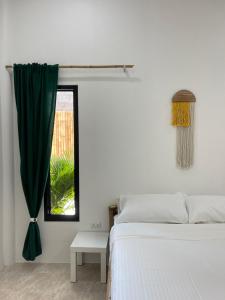 een witte slaapkamer met een bed en een raam bij Sun Stories in Thongsala