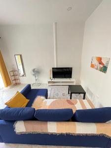 een woonkamer met een blauwe bank en een televisie bij Sun Stories in Thongsala