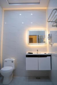 uma casa de banho branca com um WC e um espelho. em The Edition Bahawalpur em Bahawalpur