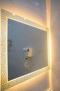 a mirror in a bathroom with a toilet paper dispenser at The Edition Bahawalpur in Bahawalpur