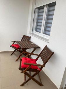 two chairs with red cushions sitting next to a window at Apartman Enigma in Ruma