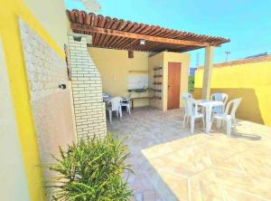 un patio con sillas blancas y una mesa y un edificio en Chalés Sons do Mar en Barra do Cunhau