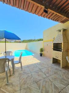 eine Terrasse mit einem Tisch, einem Grill und einem Pool in der Unterkunft Chalés Sons do Mar in Barra do Cunhau