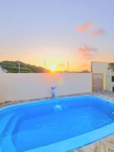 una piscina azul con puesta de sol en el fondo en Chalés Sons do Mar en Barra do Cunhau