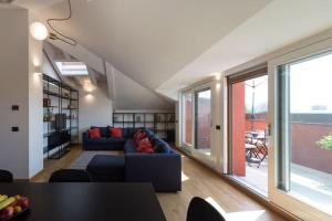 een woonkamer met een blauwe bank en een aantal ramen bij attico in un'oasi di verde sui navigli in Milaan
