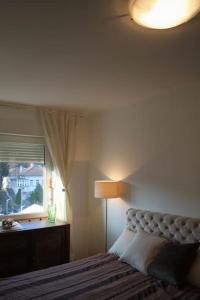 a bedroom with a bed and a lamp and a window at Cozy with parking in Zemun
