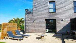 dwa krzesła i stół przed domem w obiekcie Villa en bois VUE MER avec jardin clos, WIFI, à 500m plage à l'Ile Grande en PLEUMEUR-BODOU REF-269 w mieście Pleumeur-Bodou +6 zdjęć