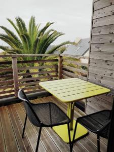 żółty stół i dwa krzesła na tarasie w obiekcie Villa en bois VUE MER avec jardin clos, WIFI, à 500m plage à l'Ile Grande en PLEUMEUR-BODOU REF-269 w mieście Pleumeur-Bodou