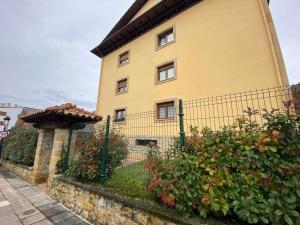 un edificio amarillo con una valla y algunos arbustos en Norabona Cangas de Onís VUT-3104-AS, en Cangas de Onís