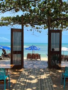 um pavilhão aberto com mesas e cadeiras na praia em Santorini Beach Hotel em Arraial d'Ajuda