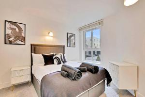 een slaapkamer met een bed en een groot raam bij Radiant 2BR Tower Bridge Oasis with Rooftop Deck in Londen