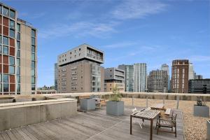 a patio with a table and chairs on top of a building at Radiant 2BR Tower Bridge Oasis with Rooftop Deck in London
