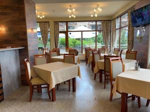een eetkamer met tafels, stoelen en ramen bij ArdoVel Park Hotel in Velingrad