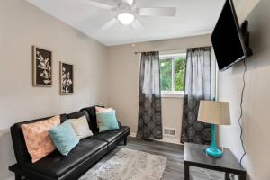 uma sala de estar com um sofá de couro preto e uma janela em Cozy Cumberland ATL Home w Hot Tub em Atlanta