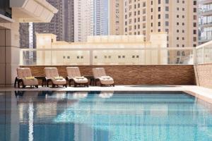 um grupo de cadeiras sentadas ao lado de uma piscina em Marina One Bedroom - KV Hotels no Dubai