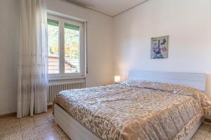 Schlafzimmer mit einem Bett und einem Fenster in der Unterkunft Casa Maggiorina, Levico Terme Ospitar in Levico Terme