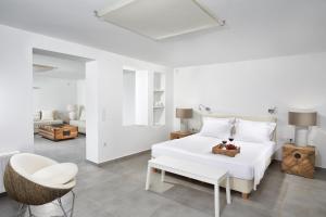 ein weißes Schlafzimmer mit einem weißen Bett und einem Stuhl in der Unterkunft Akrotiri Private Residence in Fira + 36 Fotos