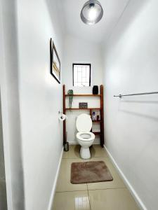 a white bathroom with a toilet and a window at Bayside Bliss Studio Apartment in Summerstrand